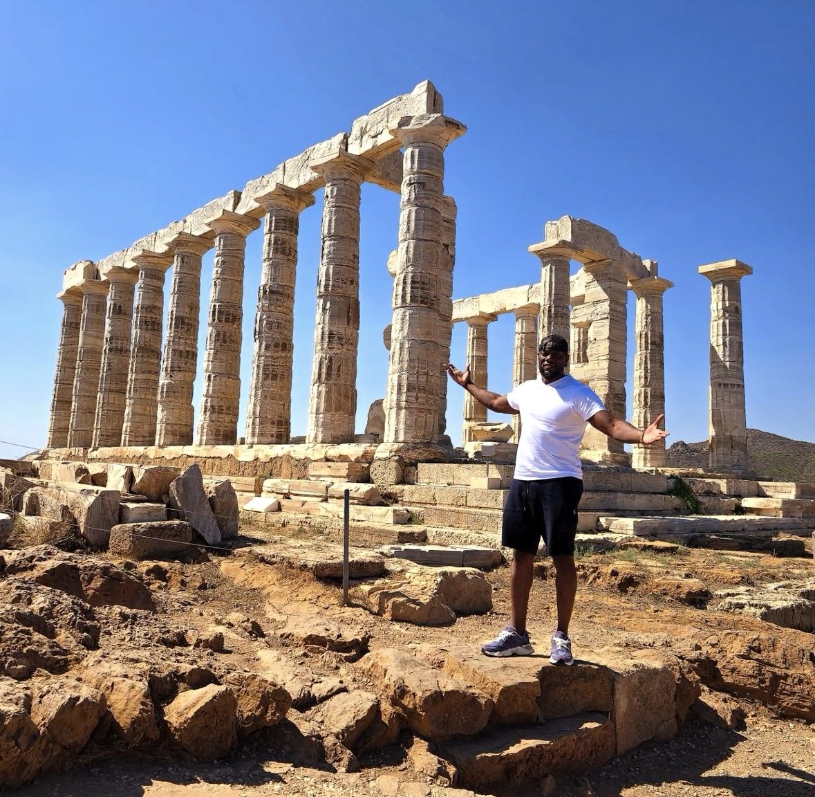एक धूप सुबह में Cape Sounion पर प्राचीन खंडहरों की खोज करने वाले आगंतुक